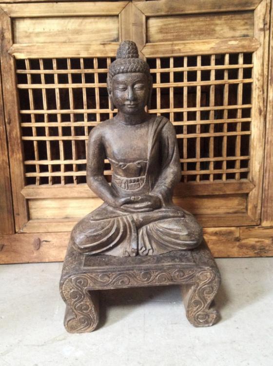 Hand carved stone Buddha sitting cross legged on hand carved stone table